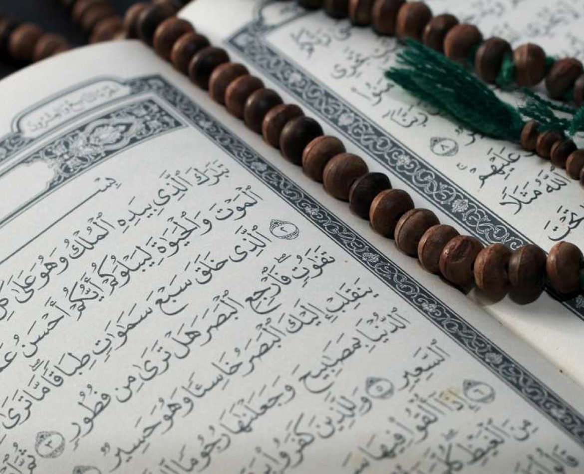 An open Quran on surah Almulk with a prayer beads on top